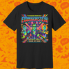 A black short-sleeve crewneck t-shirt featuring a colorful graphic print of the character Frankenstein with the text 'The Modern Prometheus! Frankenstein' and 'Creature of Curiosity Made by Man'. The shirt is displayed against a bright orange Halloween-themed background patterned with ghosts, bats, and spiderwebs.